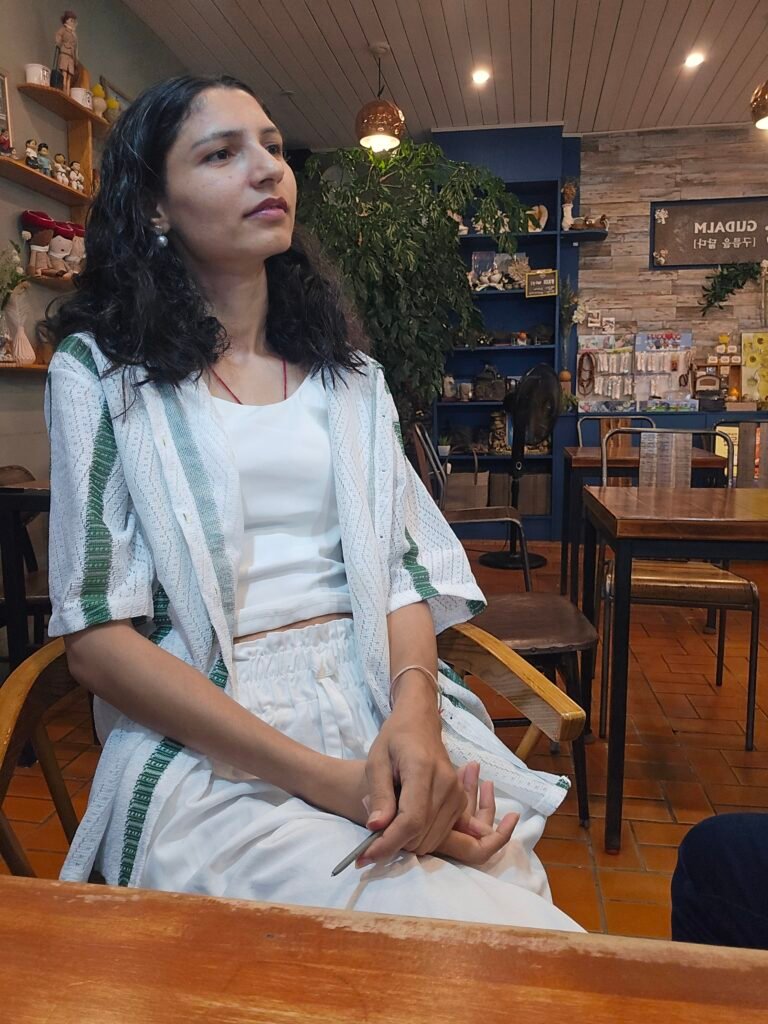 women sitting peacefully inside a cozy cafe, wearing a white dress and looking .towards sea